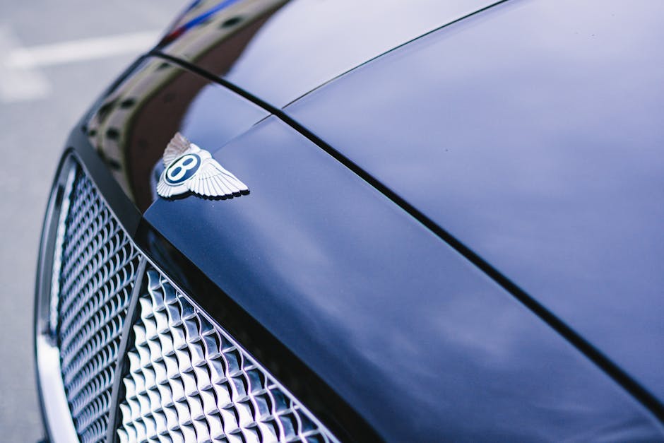 Polished luxury car hood with emblem and chrome grille.