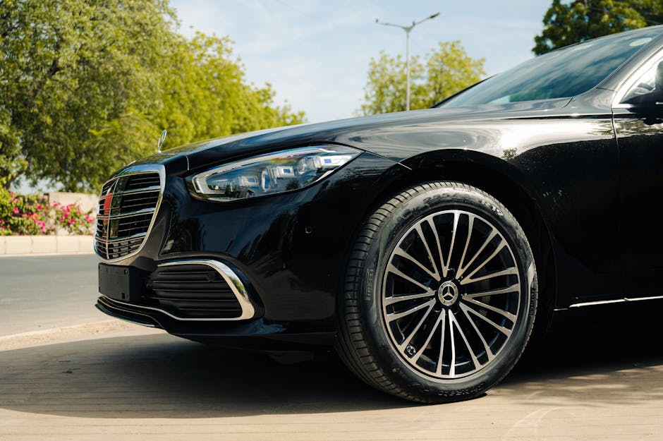 Sleek black Mercedes Benz parked on a sunny outdoor street, showcasing luxury design.